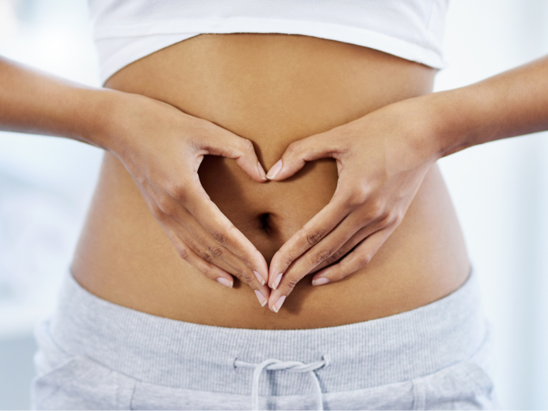 woman with a heart hand gesture over her stomach